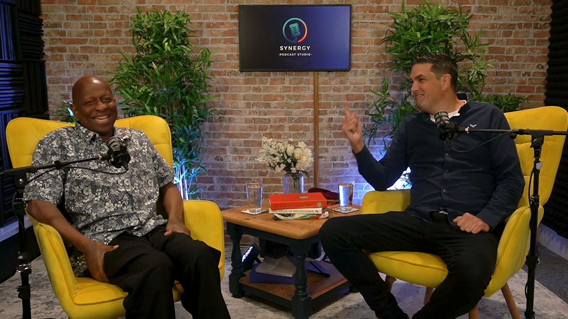 Two guests recording a podcast in the yellow chairs