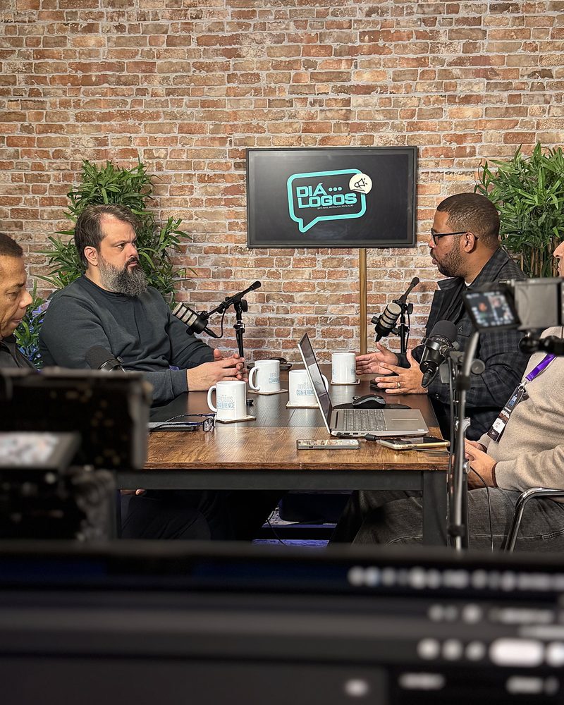 Four people recording at the table, seen from behind the camera